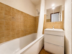 A bathroom with a bathtub, a shower, and a sink with a mirror.