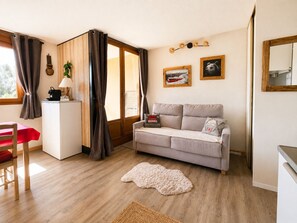 A living room with a sofa, a small table, a chair, a rug, and a sliding door.