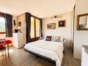 Una camera da letto con un letto, una scrivania, una sedia, una finestra con tende e decorazioni appese al muro.