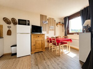 Une cuisine compacte équipée d’un four à micro-ondes, d’un petit réfrigérateur et d’une table à manger avec des chaises.
