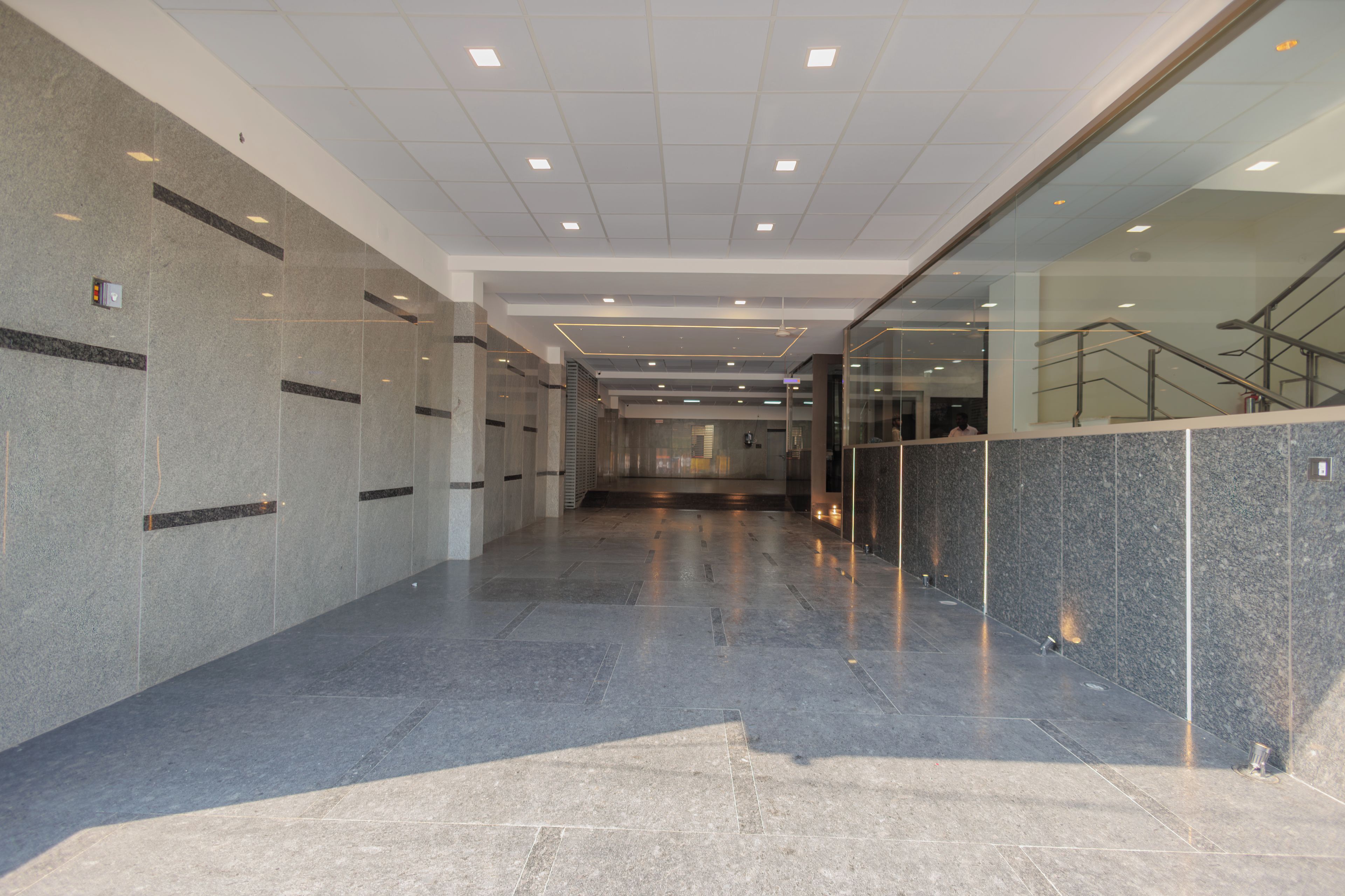 A modern interior with a long corridor, tiled walls, and a glass partition.