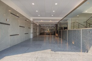 Un interior moderno con un largo pasillo, paredes de baldosas y un separador de vidrio.
