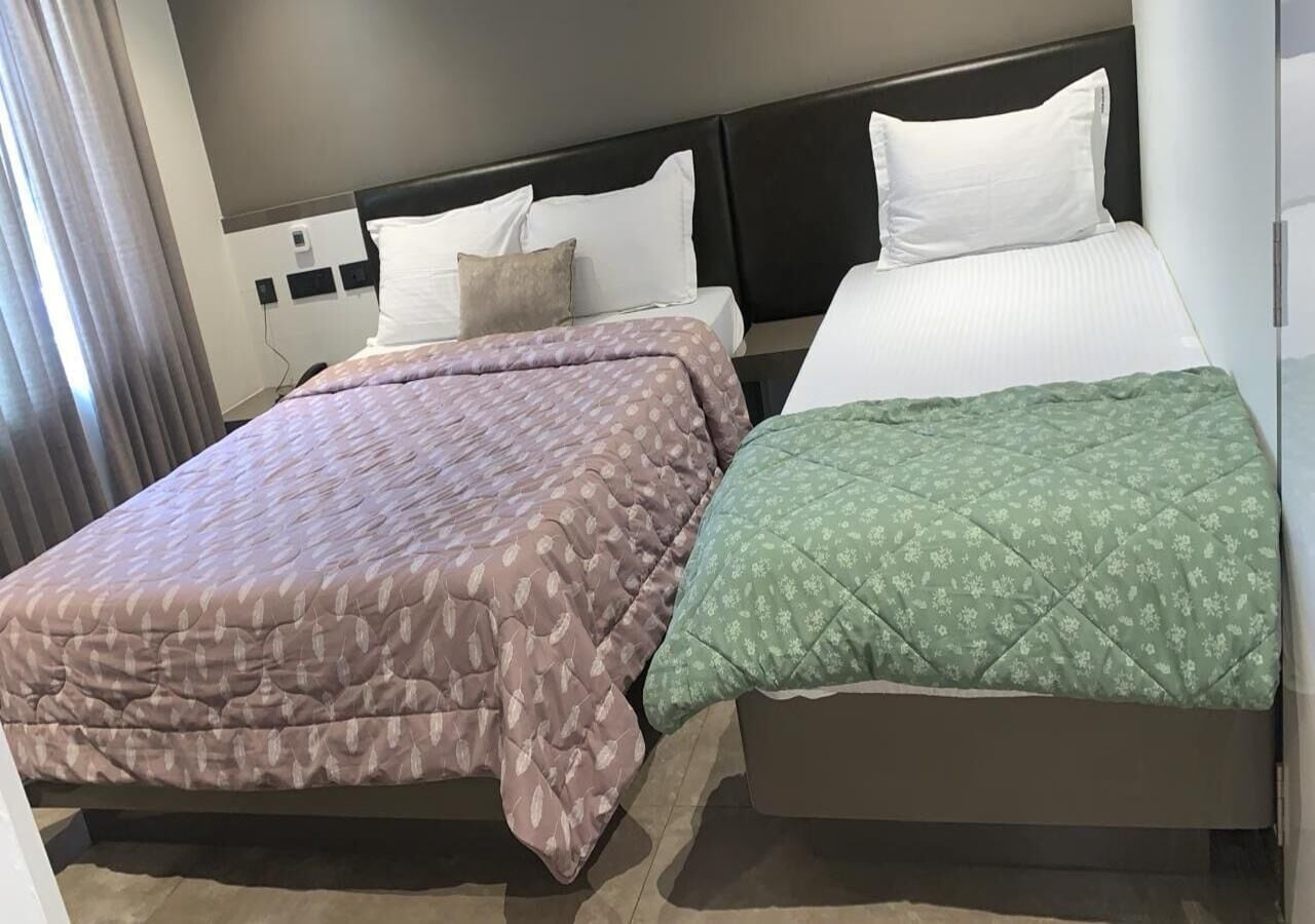 Habitación de hotel con dos camas, cada una con un edredón de diseño diferente.
