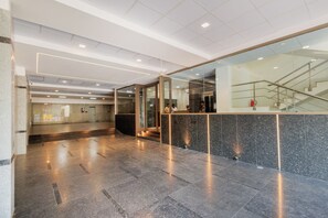 A modern lobby with a reception desk, glass doors, and a staircase. - Mas Residency (Tiruvannamalai)