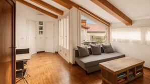 Un espacio amplio con vigas de madera, un sofá, una mesita y vistas al exterior.