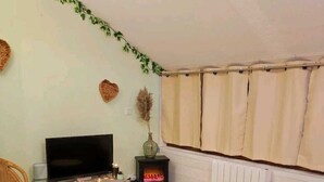 Een gezellige woonkamer met een flatscreen televisie, een open haard, een bank en een eettafel.