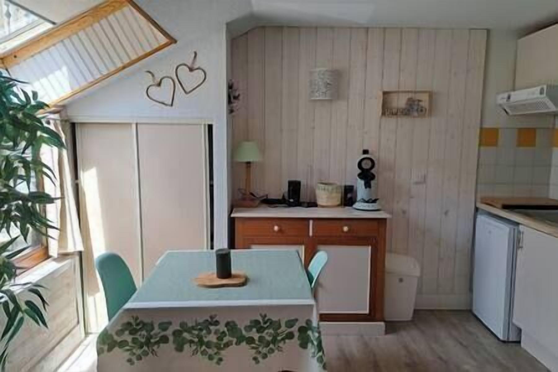 Una piccola cucina con un tavolo e sedie, un armadietto e una pianta.