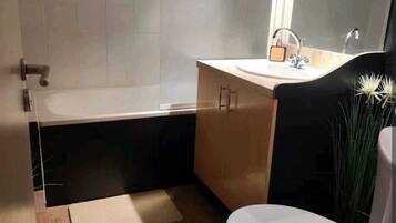 Een badkamer met een bad, wastafel en toilet.