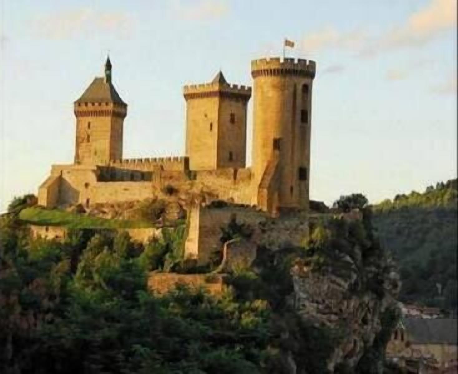 Un castillo con dos torres y una bandera en la cima, rodeado de vegetación y un acantilado.