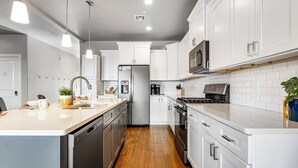 A modern kitchen with white cabinets, stainless steel appliances, and a wooden floor. - Zion Village 251|Private Pool, Xbox, Grill, Resort Amenities, and more! (Hurricane)