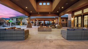 An outdoor patio area with wicker furniture, a fire pit, and a stone fireplace. - Zion Village 251|Private Pool, Xbox, Grill, Resort Amenities, and more! (Hurricane)