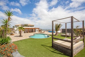 A pool area with a wooden structure, a house in the background, and a clear sky. - Volcanoa: Holiday Home with Ocean & Volcano Views (Villaverde)