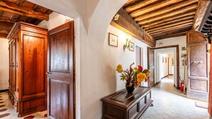 A hallway with wooden doors, a console table with flowers, and a tiled floor. - Apartment 'Green  Siena' with Shared Pool, Private Terrace and Wi-Fi (Siena)