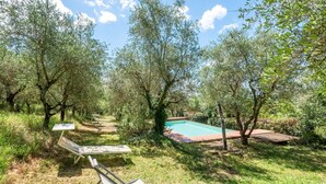 A backyard with a swimming pool, trees, and outdoor furniture. - Apartment 'Green  Siena' with Shared Pool, Private Terrace and Wi-Fi (Siena)