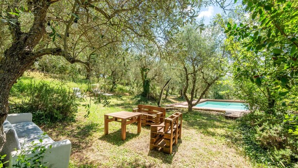 A garden with a wooden table and chairs, a stone bench, and a swimming pool. - Apartment 'Green  Siena' with Shared Pool, Private Terrace and Wi-Fi (Siena)