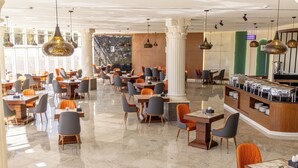 A spacious hotel lobby with multiple dining areas, a reception desk, and a large window providing natural light. - vista hotel (Tabuk)