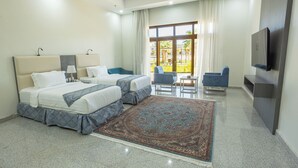 A hotel room with two beds, a TV, a desk, and a view of the outdoors. - vista hotel (Tabuk)