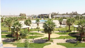 A hotel with a pool, palm trees, and a clear sky. - vista hotel (Tabuk)