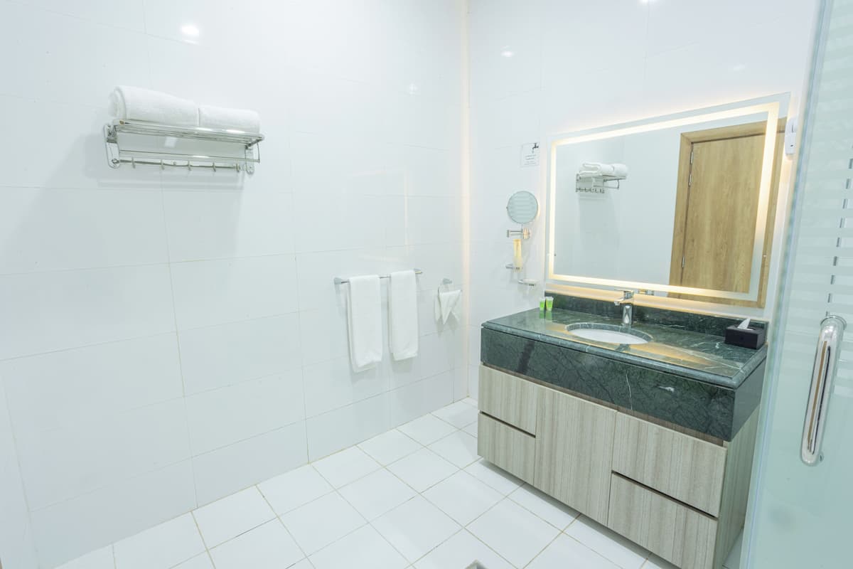 A modern bathroom with a glass shower enclosure, a marble sink, and a wooden vanity.