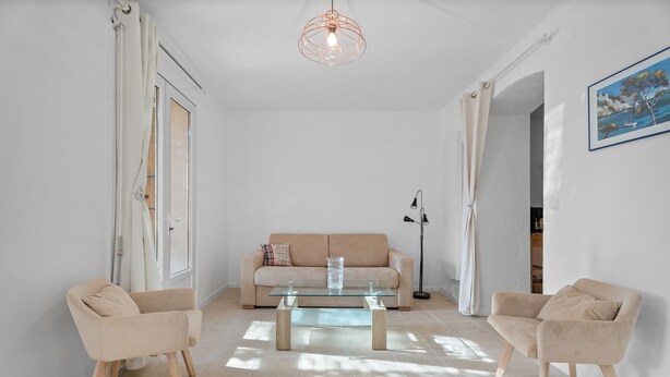 Sala de estar com sofá, duas poltronas, mesa de centro de vidro e luminária pendente.