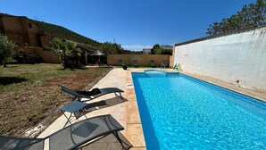 Piscina com espreguiçadeiras, um pequeno deck e uma parede branca com um personagem de desenho animado.