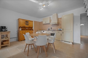 A modern kitchen with a dining table, chairs, wooden cabinets, and a patterned backsplash. - Domaine de Oliviers – Provençal house with garden and pool in Hyères, 10 min from beaches (Hyères)