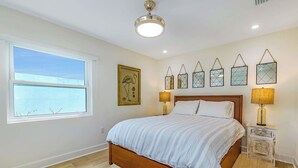 A bedroom with a large bed, a window, and decorative wall art.