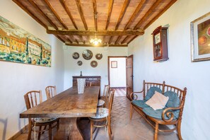Un comedor con una mesa de madera, sillas, un banco y un reloj en la pared.