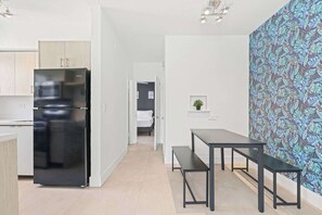 Una cocina moderna con un refrigerador negro, un comedor con banca y una pared con estampado.