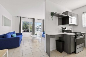 A modern kitchen with a built-in stove and oven, a blue sofa, and a white coffee table. - Discover This BR/1BA, Ideal For 4 In Miami Beach (Miami Beach)