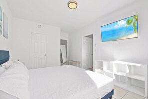 A bedroom with a bed, a TV, a white door, and a white wall. - Discover This BR/1BA, Ideal For 4 In Miami Beach (Miami Beach)