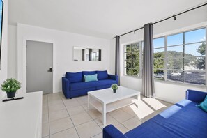 A modern living room with a sofa, a coffee table, and a large window with a view.