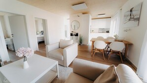 Een moderne, open woonruimte met een eethoek, keuken en een slaapkamer zichtbaar door een open deur.