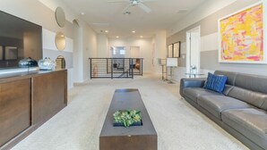 A spacious living room with a dark brown coffee table, a grey leather sofa, and a large abstract painting on the wall. - Elsa's Enchanting Escape, just 15 minutes from Disney World! (Kissimmee)
