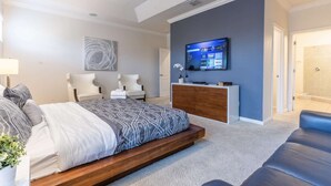A modern bedroom with a bed, two chairs, a TV, and a small desk. - Elsa's Enchanting Escape, just 15 minutes from Disney World! (Kissimmee)