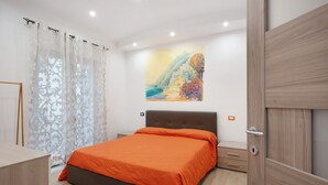 A bedroom with a bed, a nightstand, a drawer, a door, and a painting on the wall. - Apartment 'Martina' with Mountain View, Wi-Fi and Air Conditioning (Agerola)