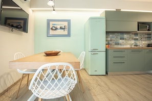 Una cucina moderna con un tavolo di legno, sedie bianche, un frigorifero azzurro chiaro e piastrelle a parete.