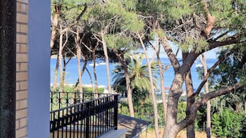 Un balcone con vista sul mare e sugli alberi.