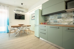 Una cucina moderna con zona pranzo, dotata di TV a schermo piatto, frigorifero in stile vintage e pannelli decorativi in piastrelle.