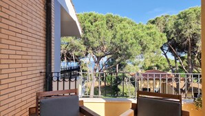 A balcony with two wooden chairs, a brick wall, and a view of trees and a body of water.