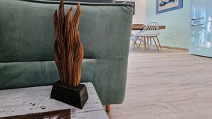A room with a green sofa, a wooden sculpture, a white chair, and a light blue cabinet.