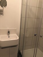 A bathroom with a white sink, a mirror, and a glass shower enclosure.