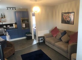 A compact living space with a kitchenette, a sofa, and a painting.