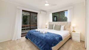A bedroom with a bed, a nightstand, a ceiling fan, and a window with curtains.