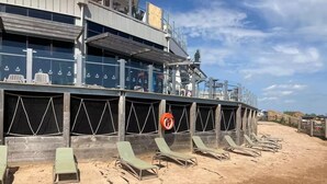 En byggnad vid stranden med flera våningar, utomhusområden med sittplatser och en livboj.