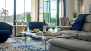 Un salon moderne doté d’un patio fermé par des baies vitrées, d’un canapé en cuir et d’une table à manger agrémentée de verres à vin et d’une bouteille.