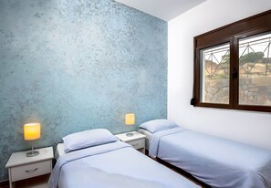 Une chambre avec deux lits, une fenêtre donnant sur un beau paysage et un mur à motifs.