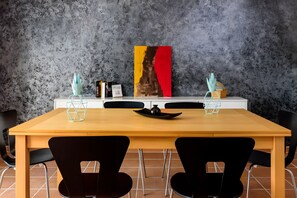 Une table à manger avec deux chaises, un tableau et un vase posé sur la table.