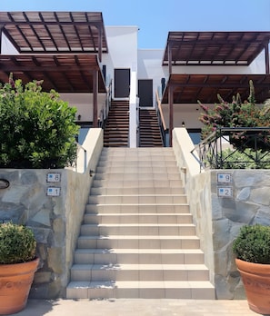 A staircase leading to a building with a modern design, stone walls, and potted plants.