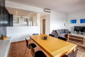 Un espace de vie moderne comprenant un coin repas, un canapé, un téléviseur et un coin cuisine.
